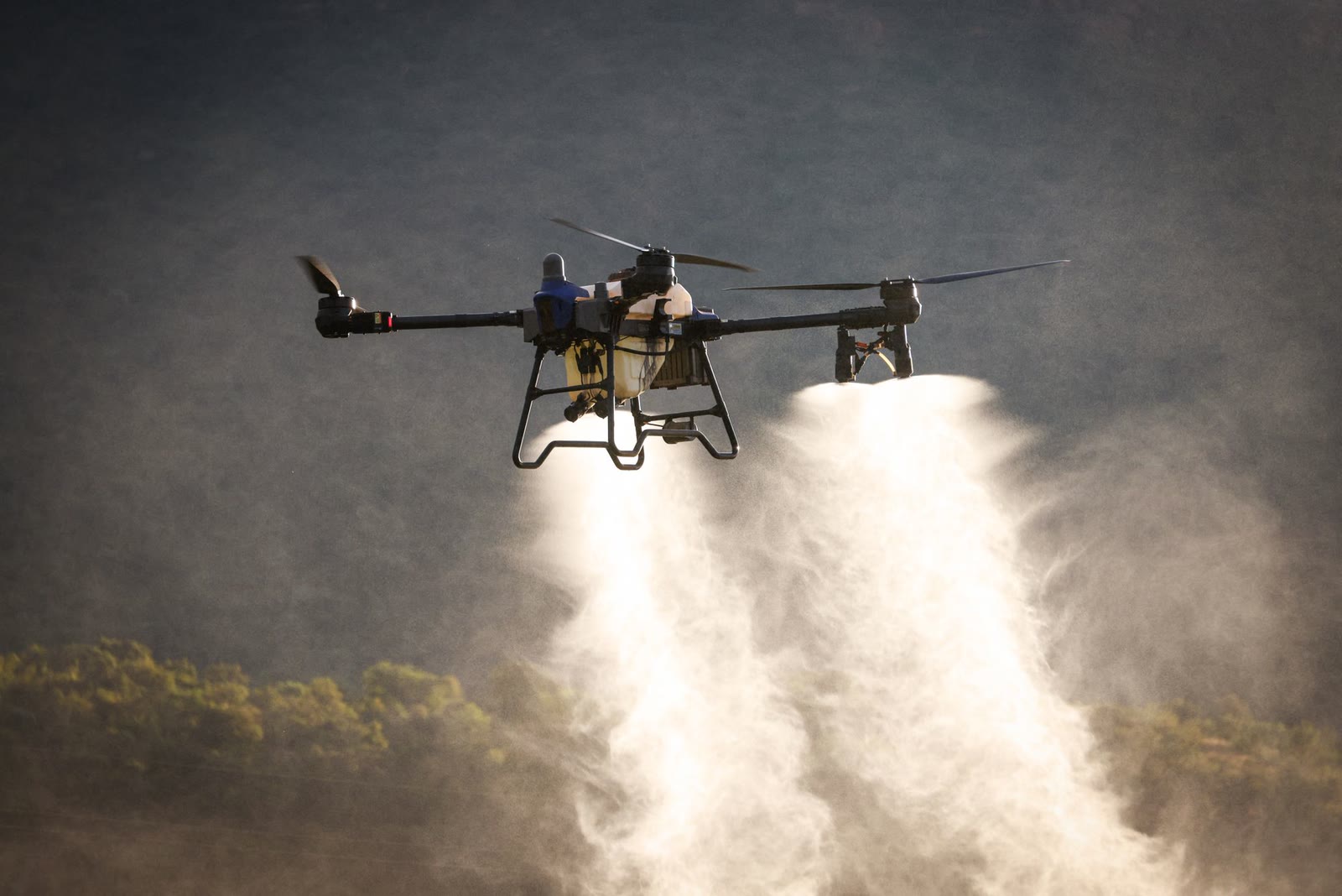 Il drone distribuisce il prodotto in nebbia fine sul campo, controluce all'alba