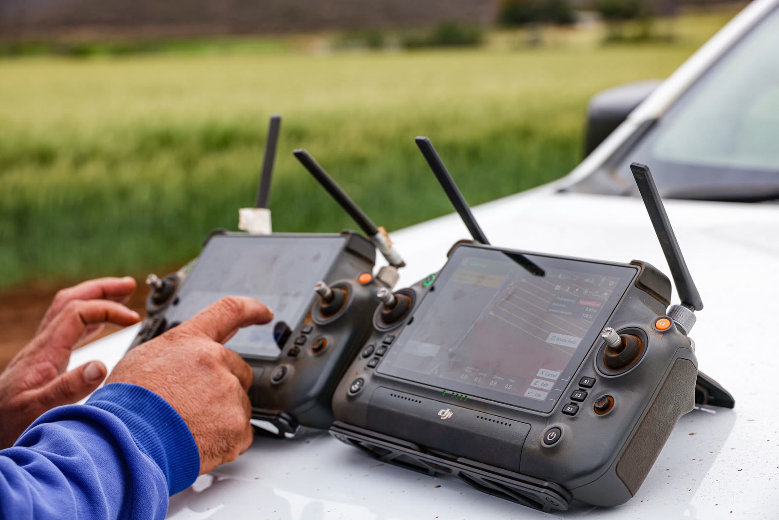 Le mani del pilota sul radiocomando, con il campo dietro